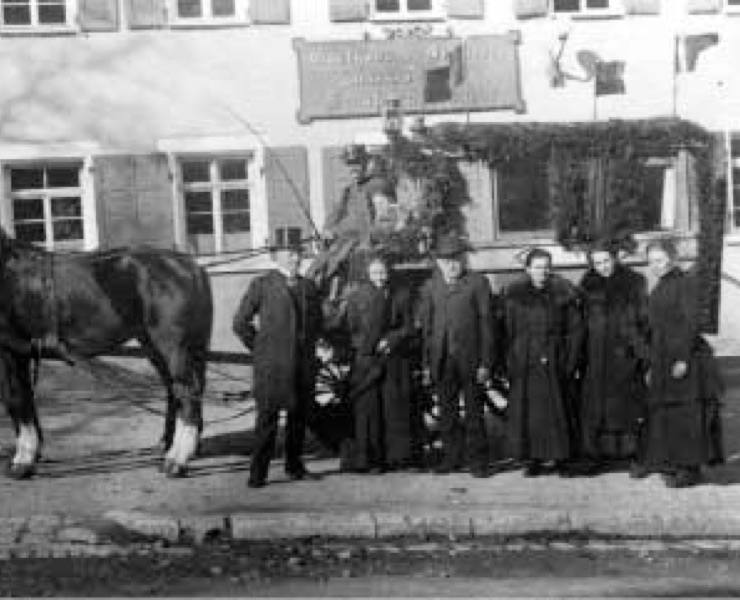 Das Foto zeigt Leonhard Johann Mayer mit seiner Frau und seinen vier Kindem vor der Postkutsche um 1910. Links mit Zylinder: Leonhard Mayer.